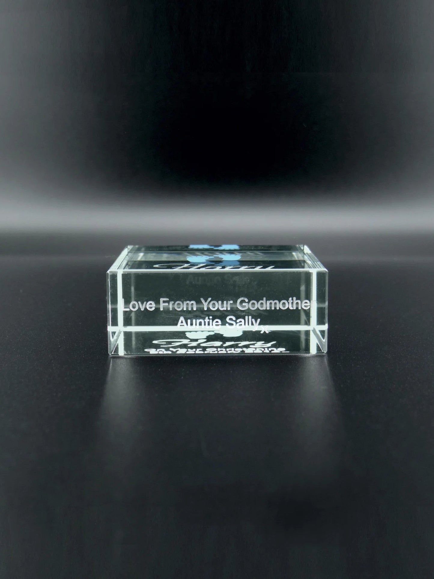 This image shows a small, jade glass block with a smooth, polished surface. It is engraved with the message "Love From Your Godmother Auntie Sally x" in a clear a contemporary sans serif script. The block is positioned on a dark, matte surface that contrasts its transparency and the crispness of the engraved lettering. The item appears to be a personalized keepsake, likely a gift commemorating a special relationship or occasion.