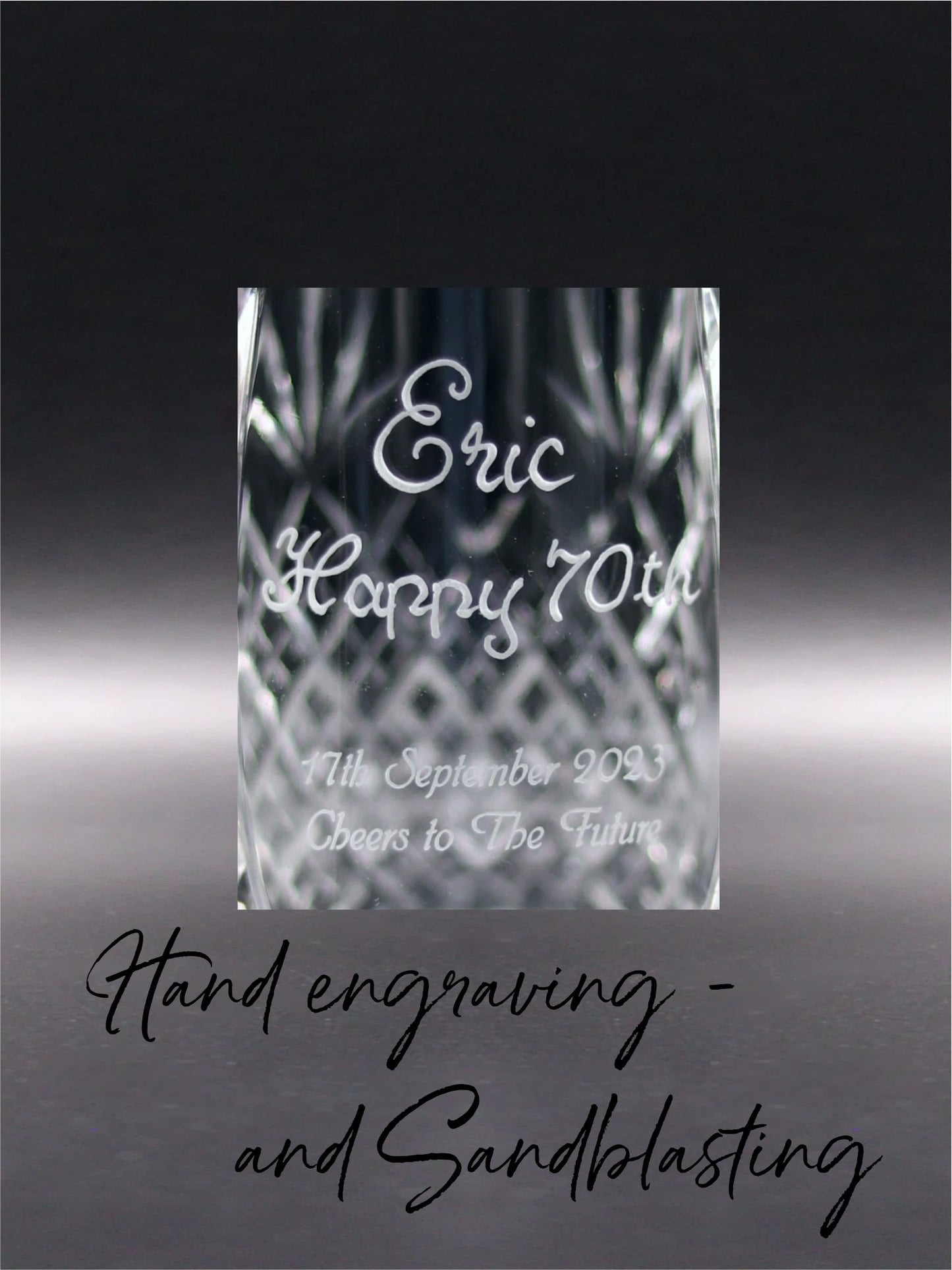 A crystal glass elegantly etched with the name "Eric" above "Happy 70th" in a hand-engraved, flowing cursive that stands out with clarity and shine. Below, in a contrasting texture, a sandblasted message reads "11th September 2023, Cheers to The Future," offering a heartfelt toast to commemorate a significant milestone. The combination of hand engraving and sandblasting creates a dynamic, tactile experience and visual depth.