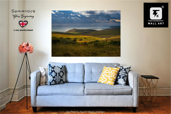 A powder blue sofa with decorative pillows in a living room setting, featuring a large wall art of a scenic Belle Tout landscape.