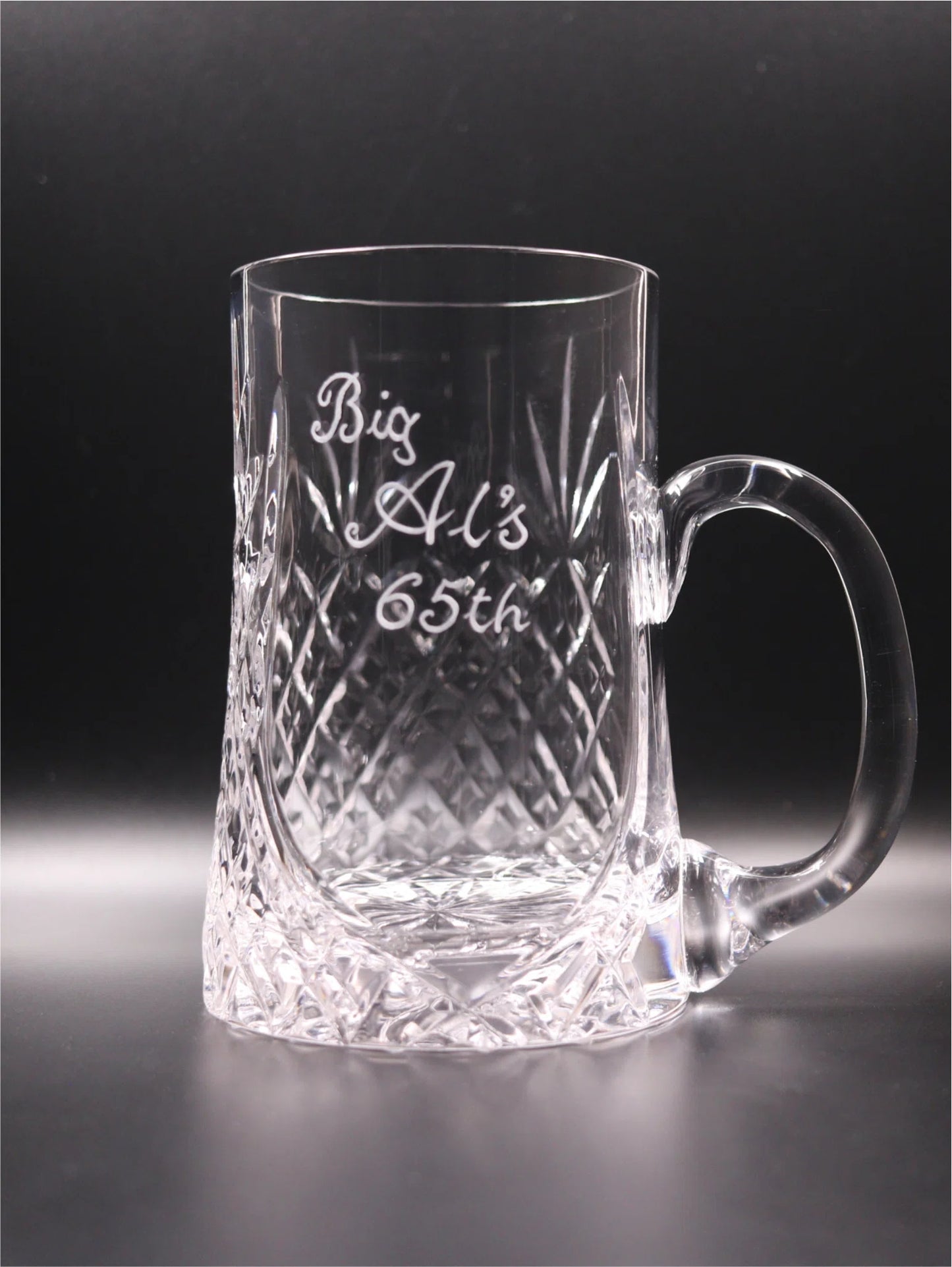 A 24% crystal pint tankard with a diamond-cut pattern on the lower half, featuring a personalized engraving that reads "Big Al's 65th" hand engraved.