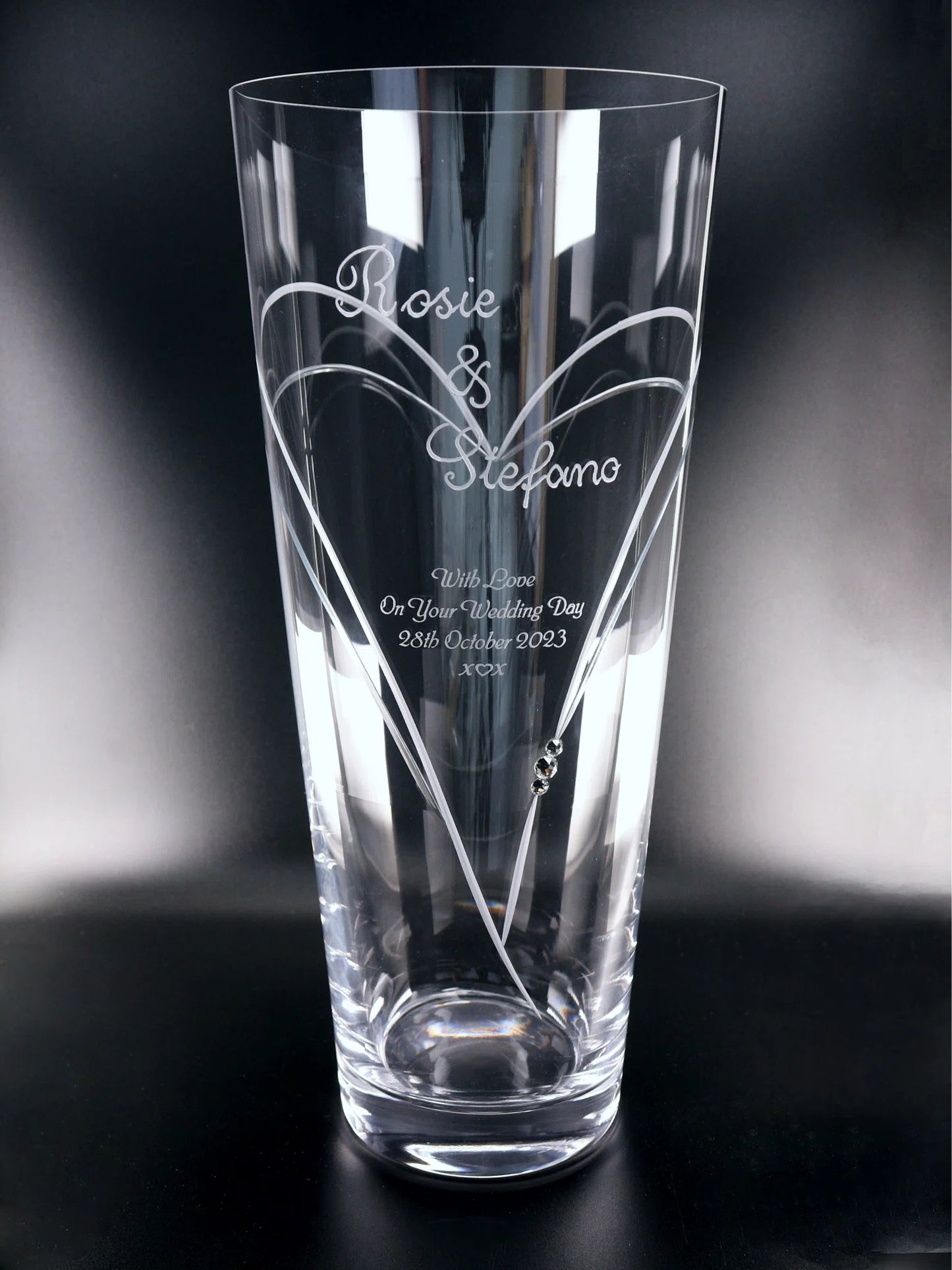 A tall, 30cm Diamante Conical Vase with Heart Shaped Cutting with 3 Swarovski® Crystals with "Rosie & Stefano With Love On Your Wedding Day 28th October 2023 x ♡ x" engraved amidst elegant heart-shaped designs and a pair of sparkling crystals, creating a beautiful, personalized wedding memento.