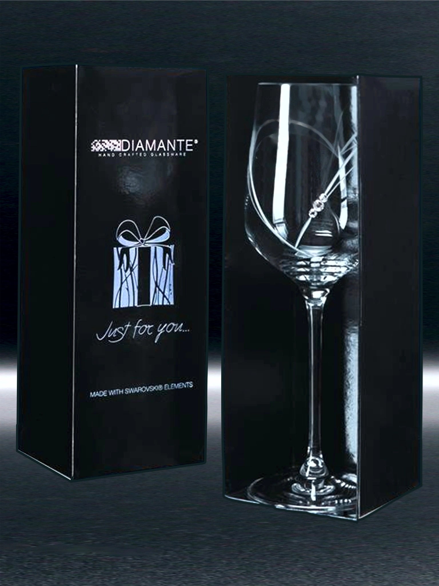 A glass before engraving, a heart is cut into the glass and three Swarovski crystals. The glass is showcased next to its packaging, a DIAMANTE box with holographic text reading "good things come in small packages Just for you…" and the promise of Swarovski crystal embellishment.
