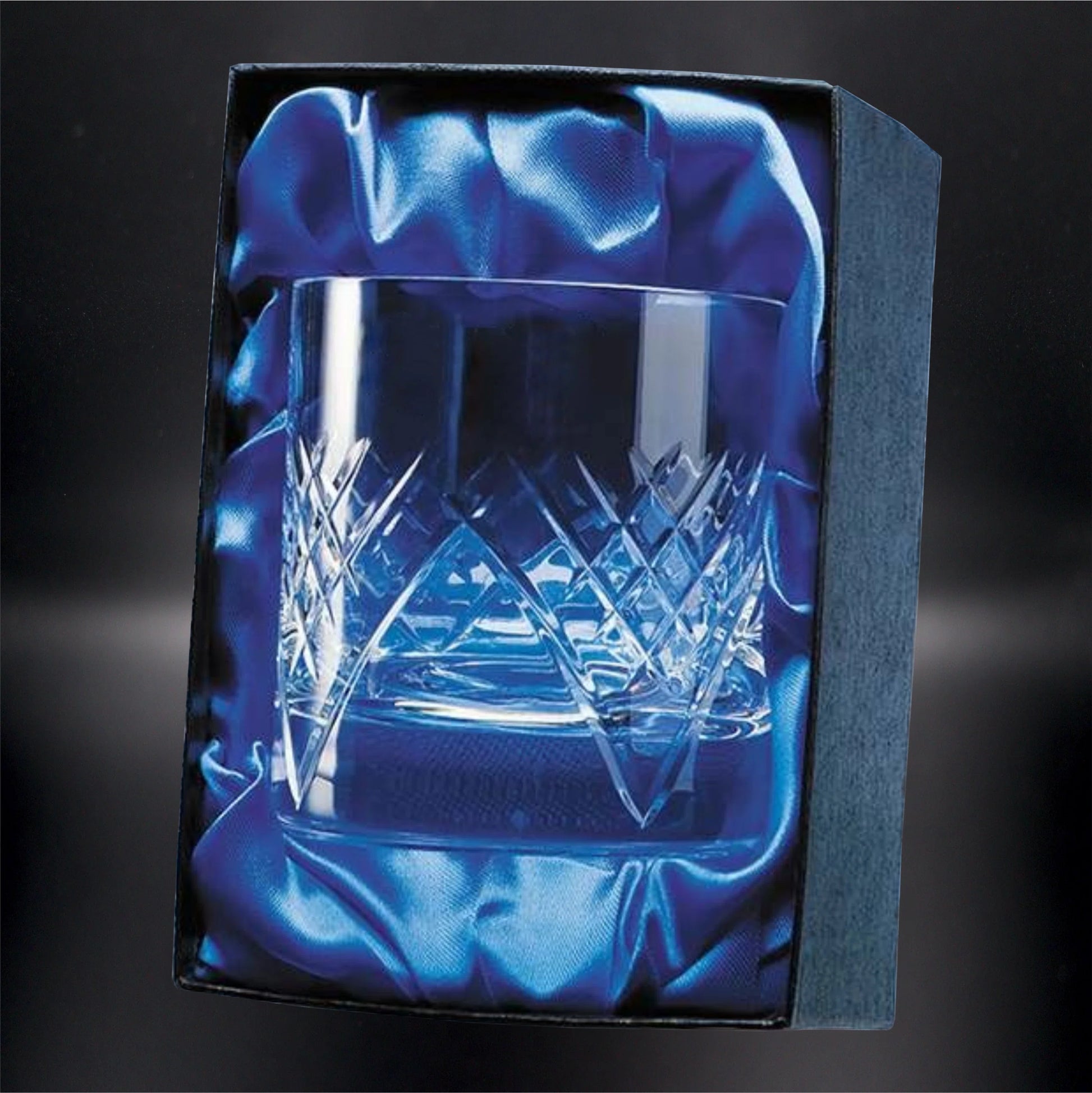 A crystal whiskey glass with a classic diamond cut design, presented in a gift box with rich blue satin lining, emphasizing the glass's sparkling facets and premium quality, perfect for a distinguished gift or keepsake.